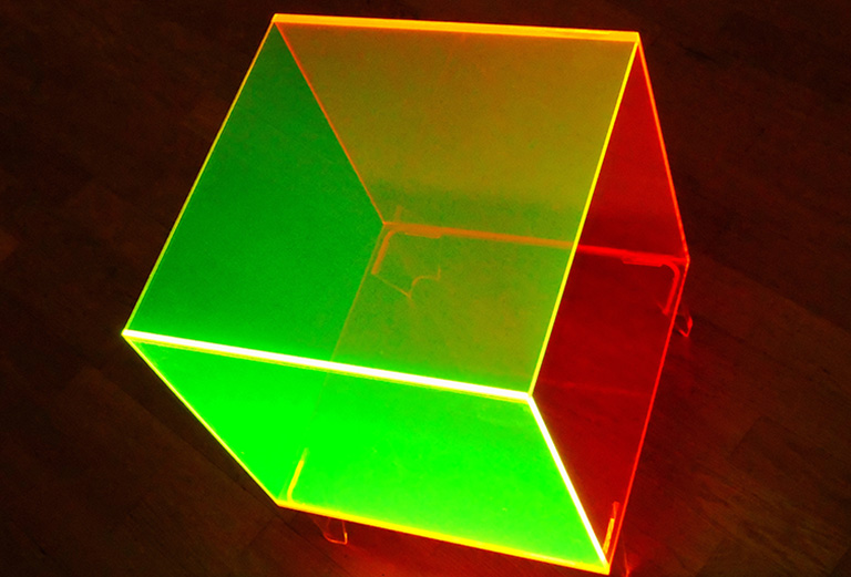 Medium shot of a fluorescent neon yellow and orange side table in a studio shot.