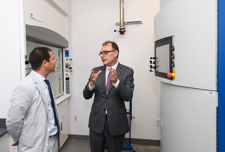 photo of David Lehman, commissioner of the department of economic and community development (DECD), left, and Pamir Alpay, director, check out 3D metal printing machines on a tour of the Innovation Partnership Building (IPB) on May 22, 2019. (Peter Morenus/UConn Photo)